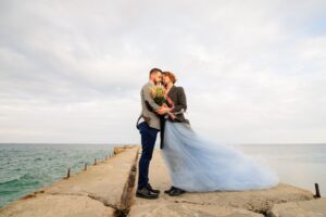 Wedding photo session of a couple on the seashore. Blue wedding dress on the bride.